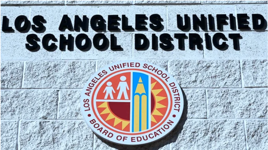 A white washed brick wall with metal letters that read "Los Angeles Unified School District" and beneath it the LAUSD logo