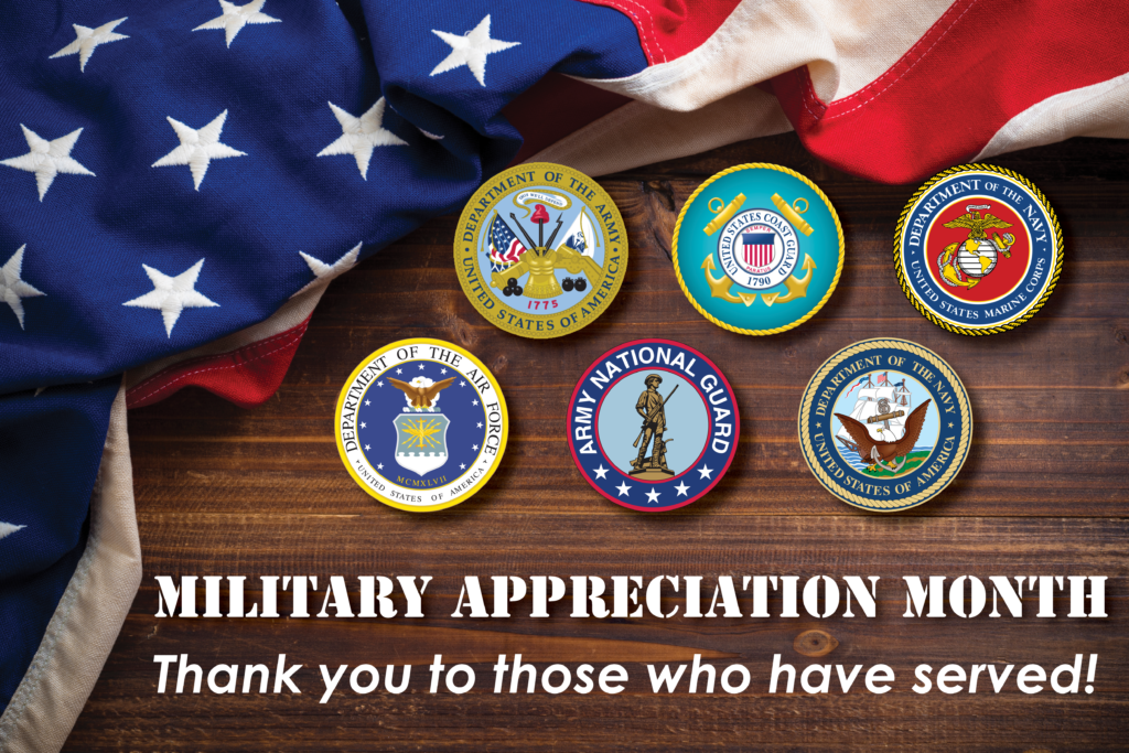Military Appreciation Month - A flyer of a dark wood table with an american flag draped in the top left hand corner. The six seals representing the different branches of the military are in the center of the table with the words: "Military Appreciation Month. Thank you to those who have served!