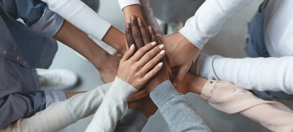 An image of a group of people with thier hands in a team huddle.An employee owned company (ESOP)- is all about teamwork.