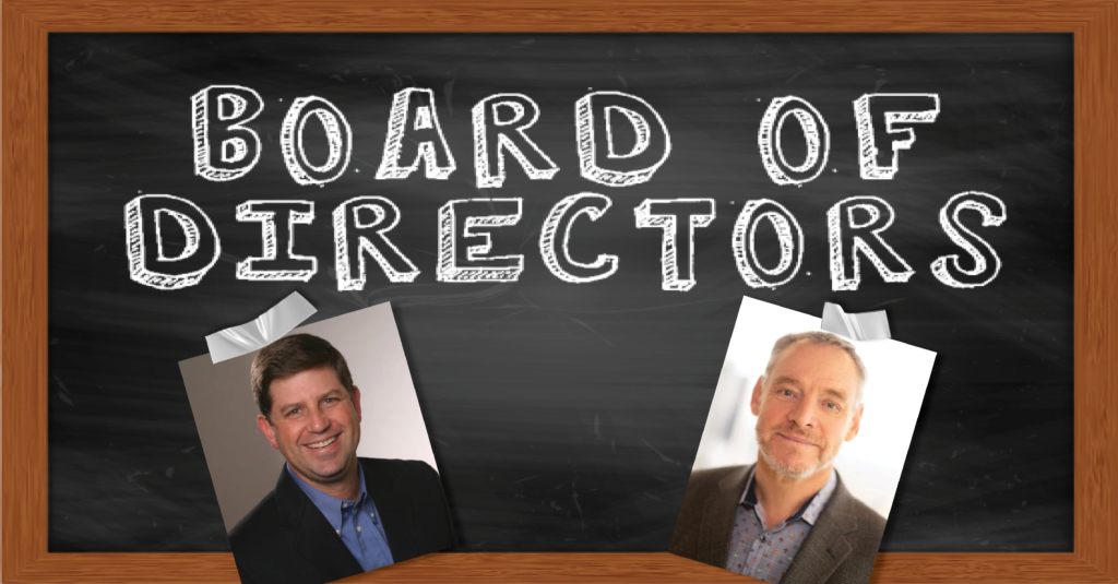 A blackboard that has "Board of Directors" written in white chalk, below the words are the headshots of two men with tape sticking the photos to the blackboard.